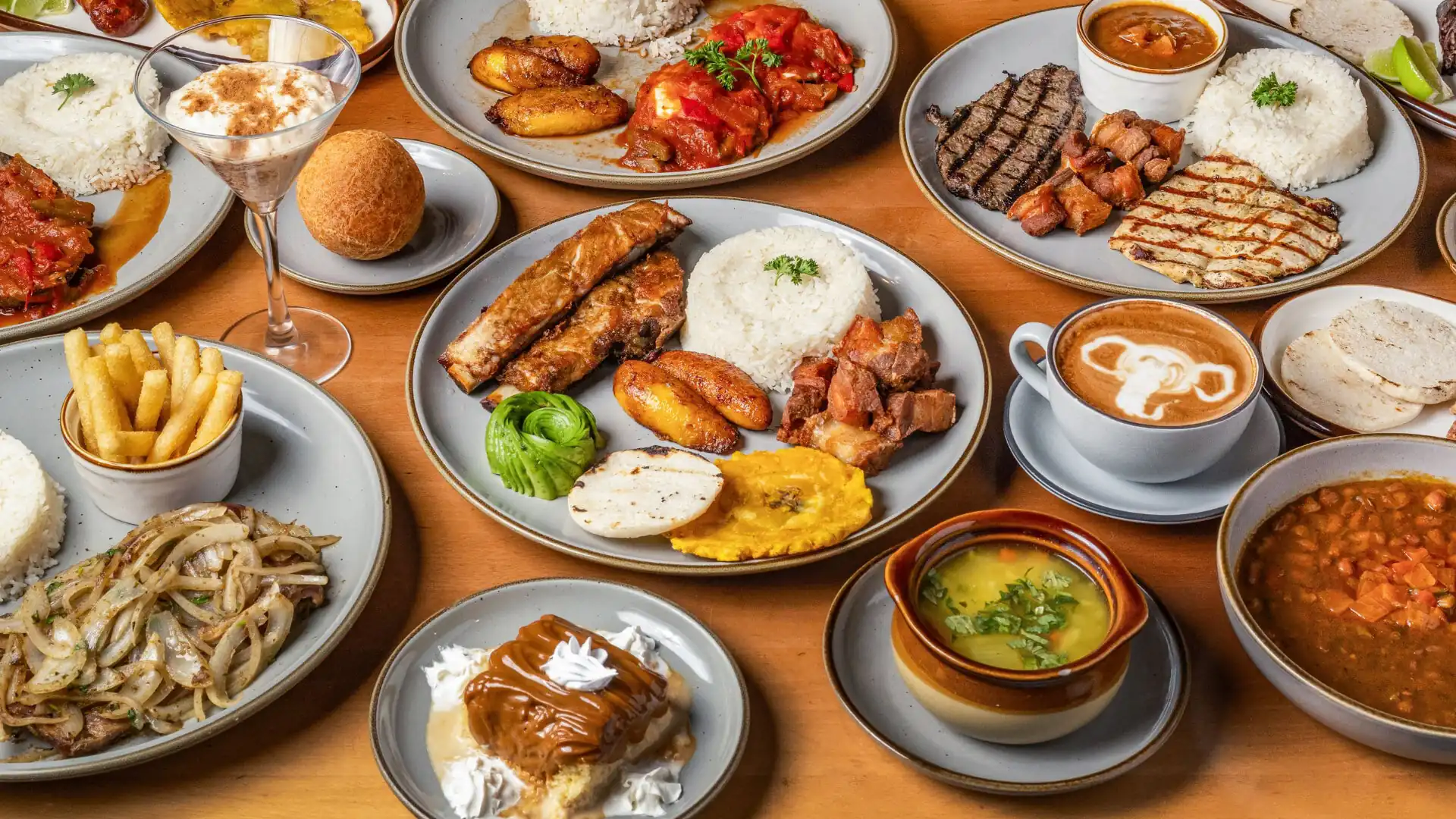 Table full of Colombian dishes: bandeja paisa, sancocho, arepas, empanadas and coffee